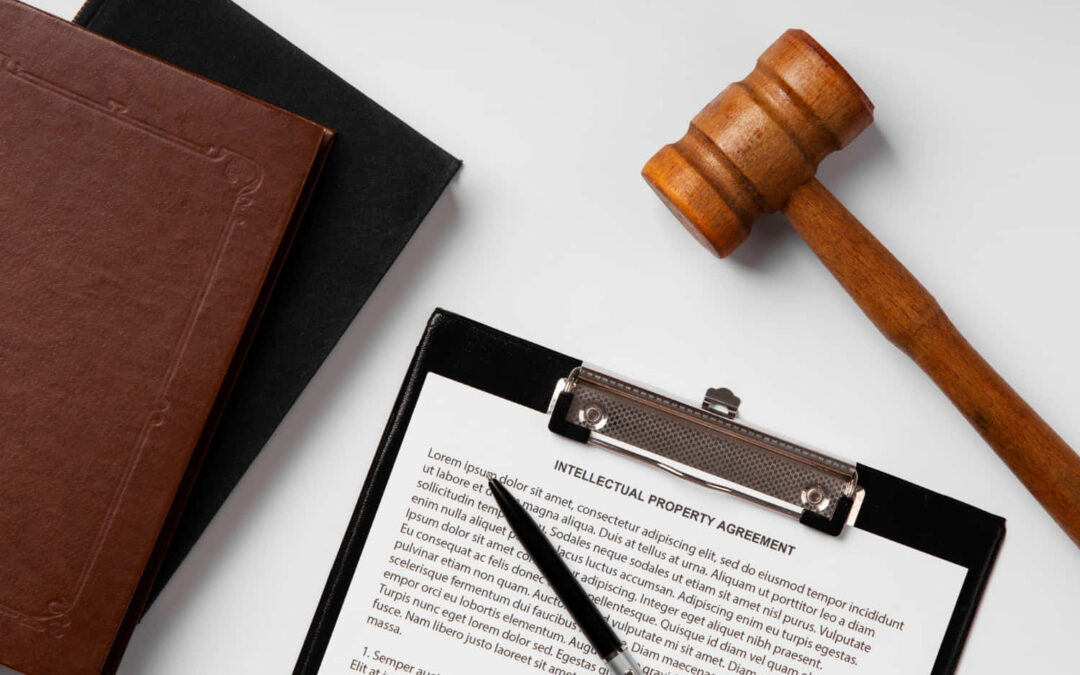 un marteau de juge, un bloc note avec des inscriptions légales sont posées sur une table blanche